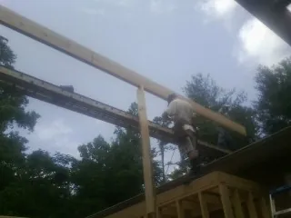 Carpenter setting a ridge beam over a new addition frame — Ice Dam Removal by Roofing Brothers in Oketo