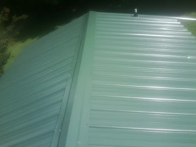 New green metal panels meeting at the ridge of a roof — Flat Roof Repair work by our crew in Oketo