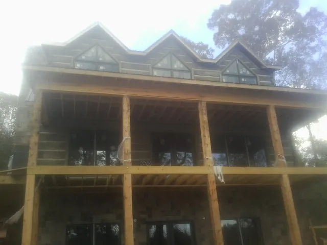 Dormers and porch framing on a large log home under construction — Roof Coating work by our crew in Oketo