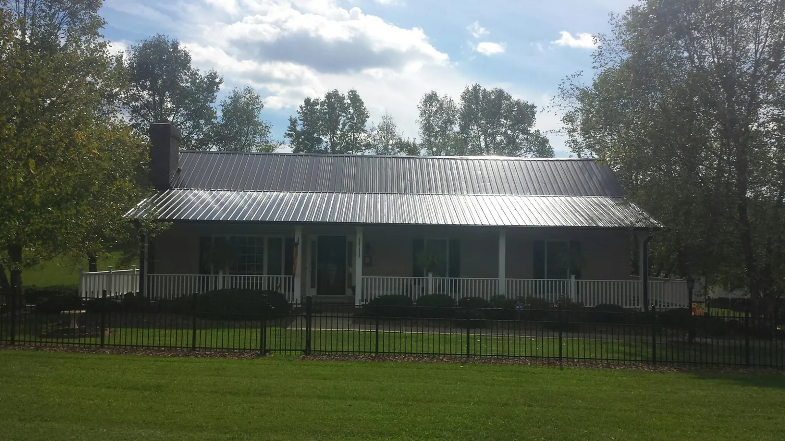 Gray metal roof on a brick ranch with a full width front porch — Gutter Guard Installation work by our crew in Oketo