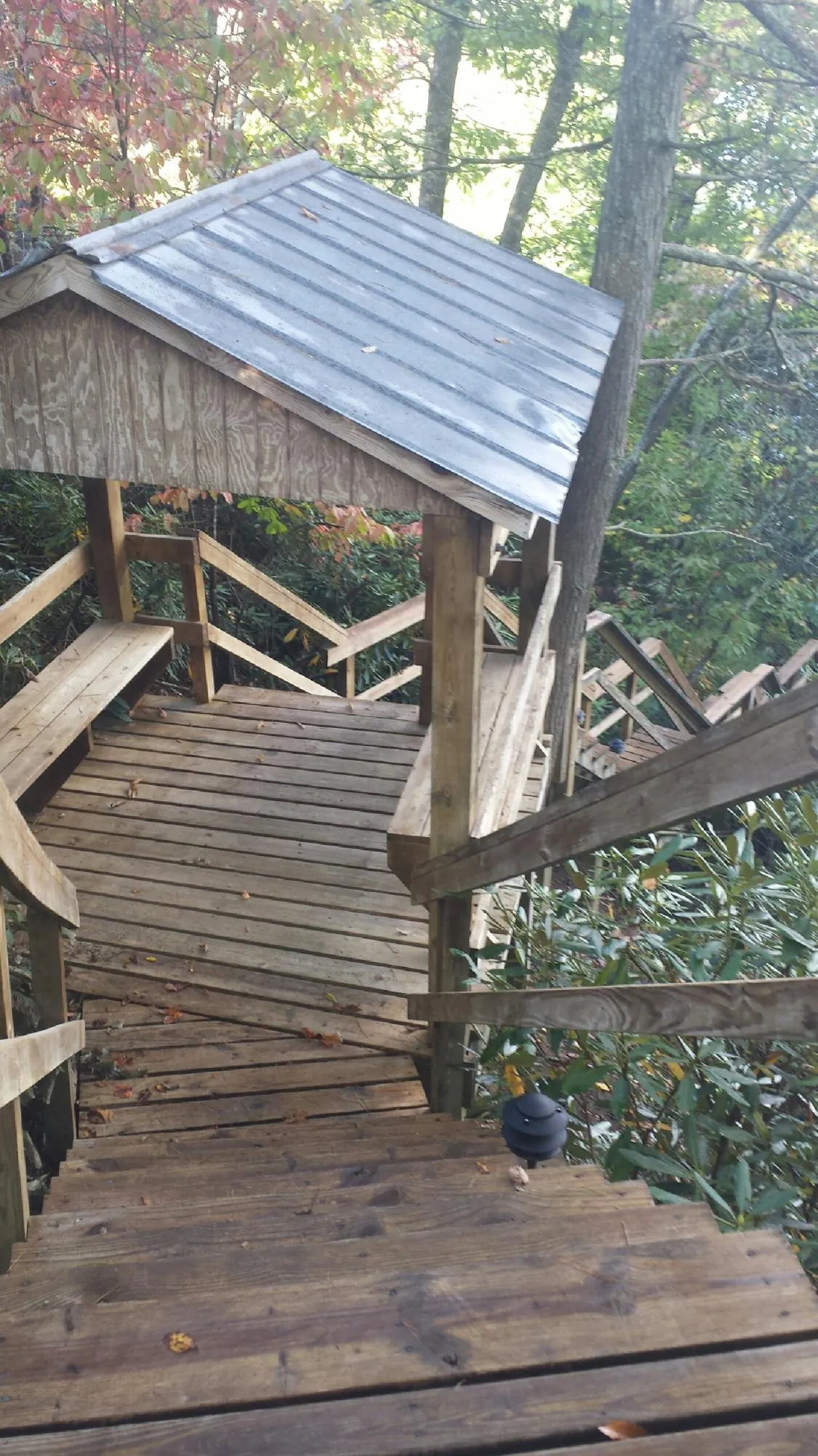 Metal roofed shelter over wooden steps on a wooded walkway — Skylight Repair & Installation work by our crew in Oketo