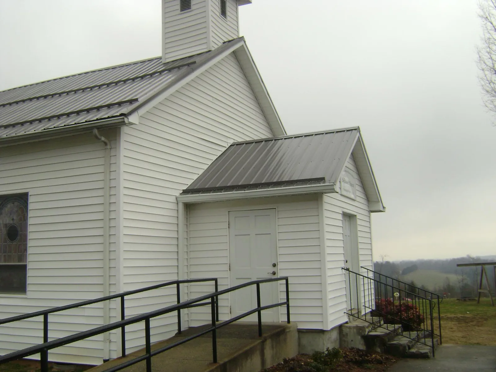 Gray metal roof on a white clapboard church with a steeple in Oketo