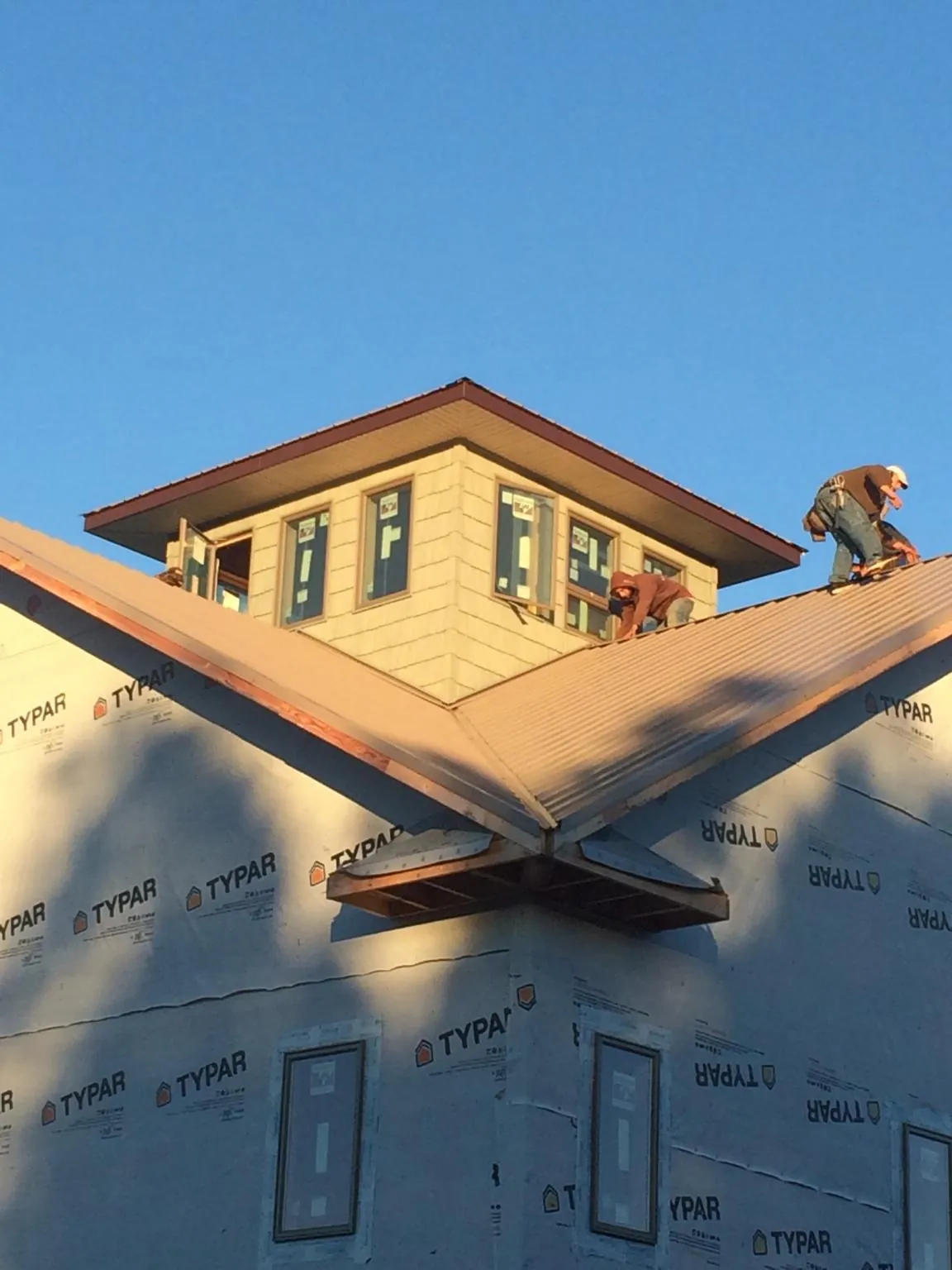 Roofers working around a rooftop cupola on a new metal roof at sunset — Roof Waterproofing in Oketo by Roofing Brothers